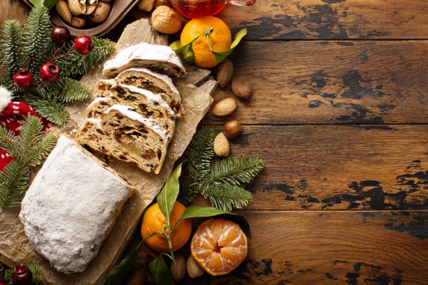 Traditional German Christmas stollen dusted with powdered sugar, sliced to reveal dried fruits and marzipan filling.