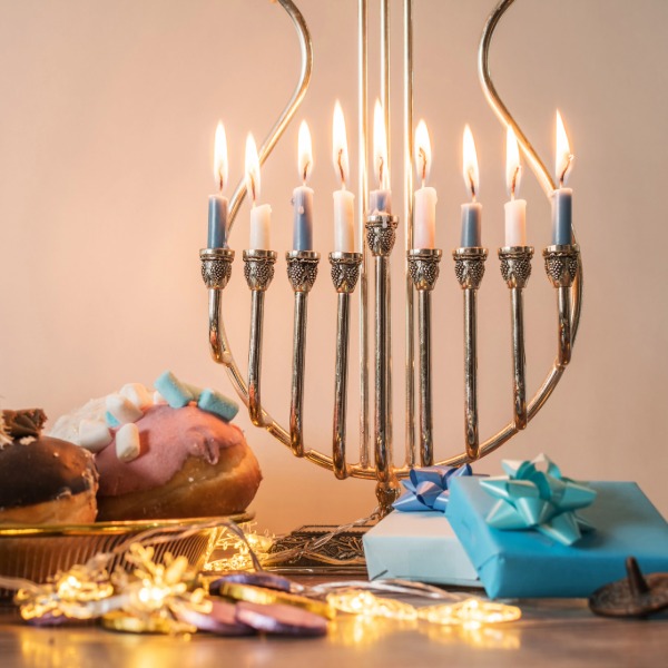 Menorah candle lit, part of a Hanukkah celebration, glowing warmly against a festive backdrop.